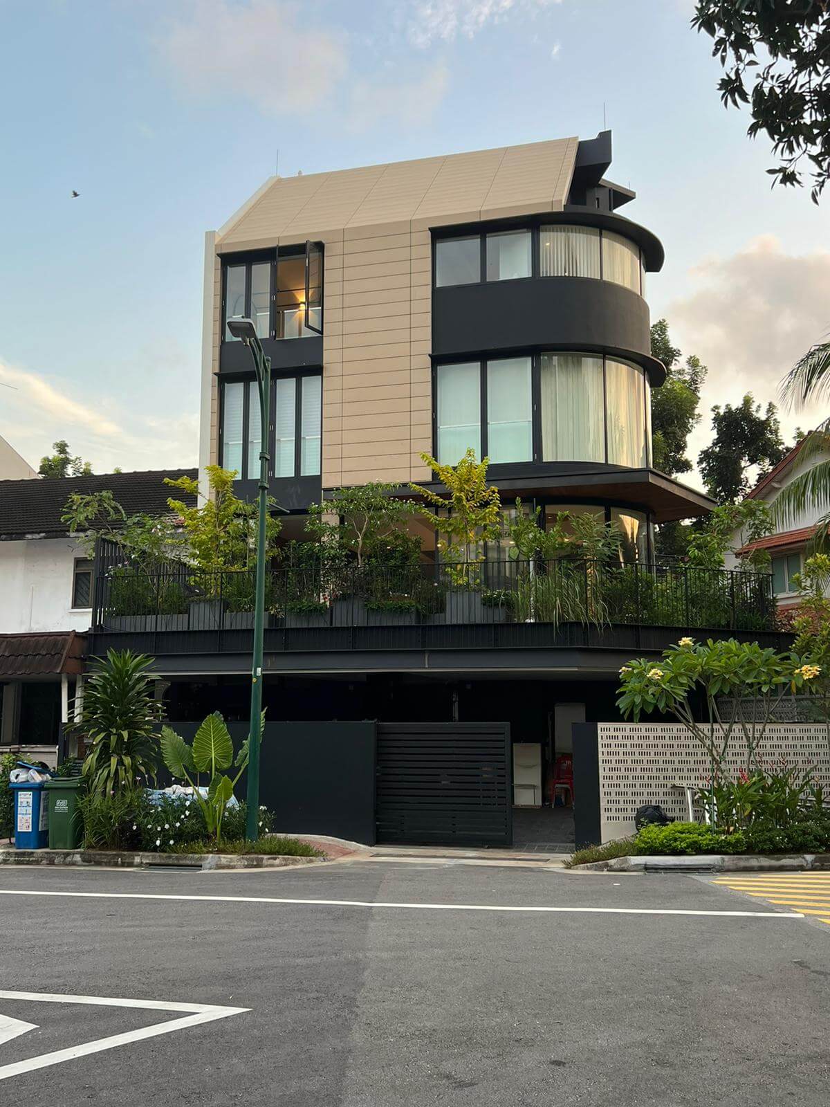 The terra-cotta paneled facade rises above a planted carporch roof terrace, with curved glass forms softening the corner facing the park.