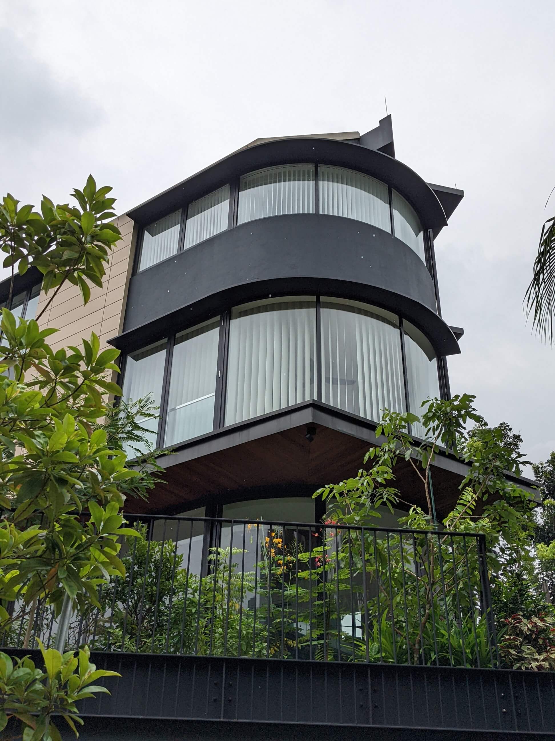 Curved glazing and sweeping fascias wrap the corner, with a timber soffit below the living level.