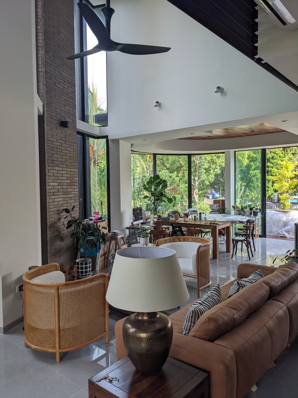 A double-storey void joins living and dining, with brick feature side walls and tall glazing sashless up-down sliding windows bringing in natural light and tree canopy views.