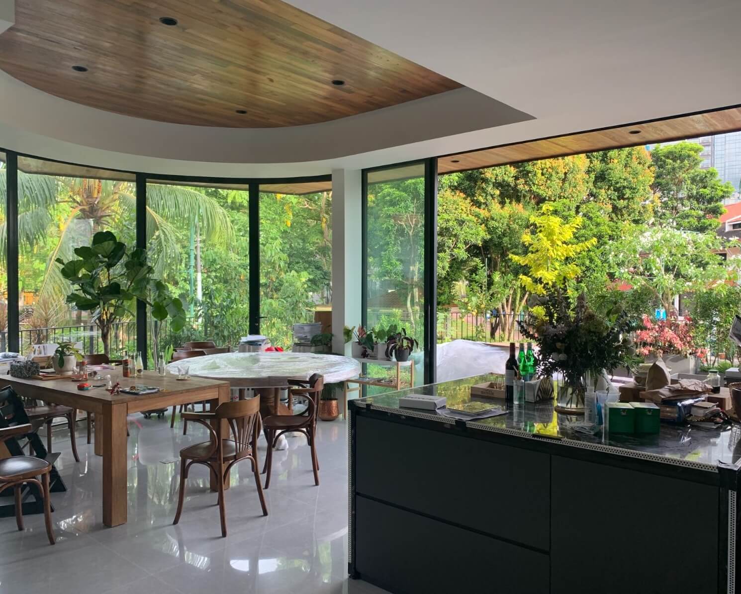 The kitchen island looks toward the dining area, where a curved timber ceiling follows the glass.