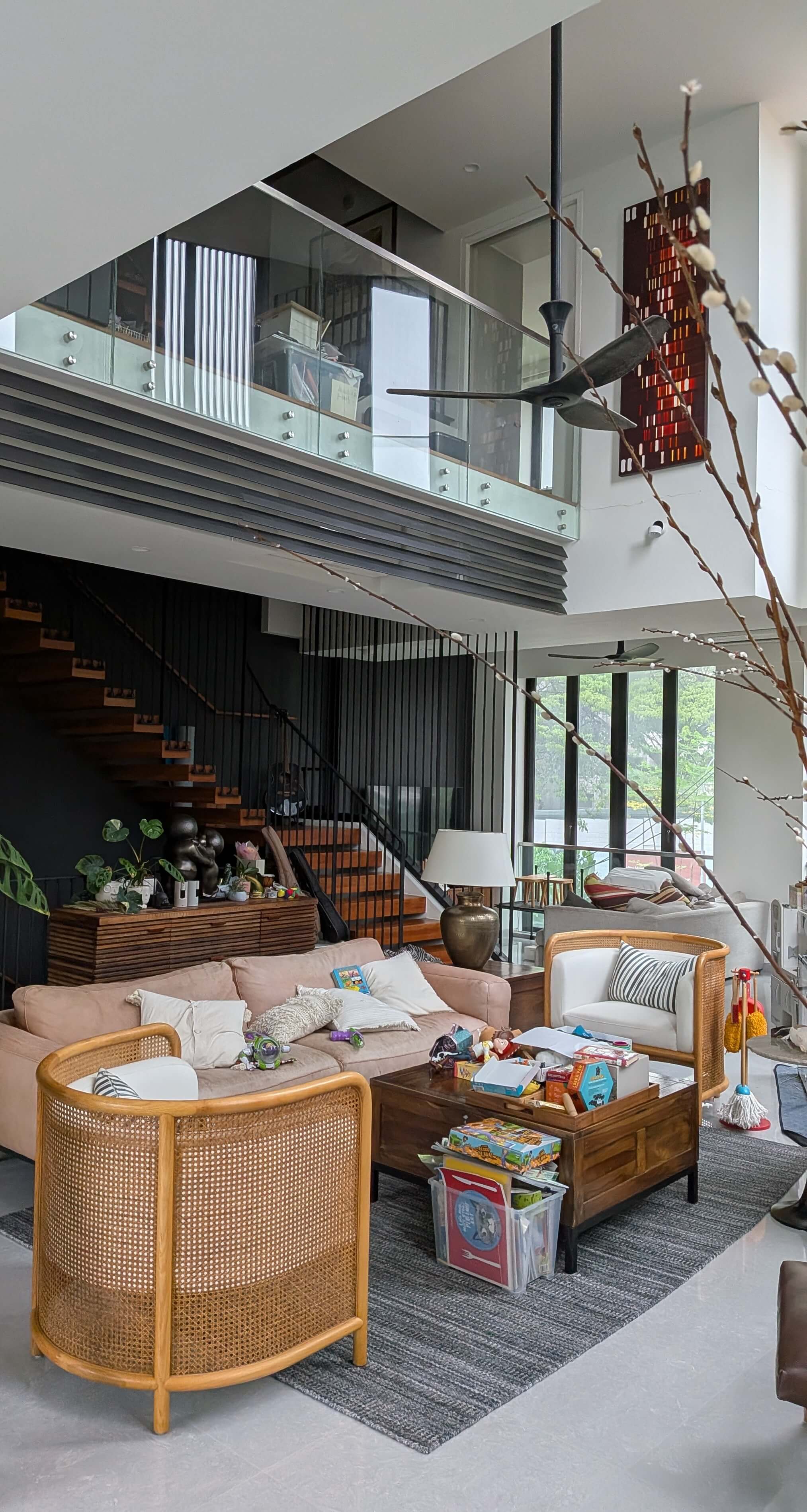 A double-volume living area is backdropped by a floating timber stair and a bridge between the Master Bedroom suite and Master study overlook the mezzanine.